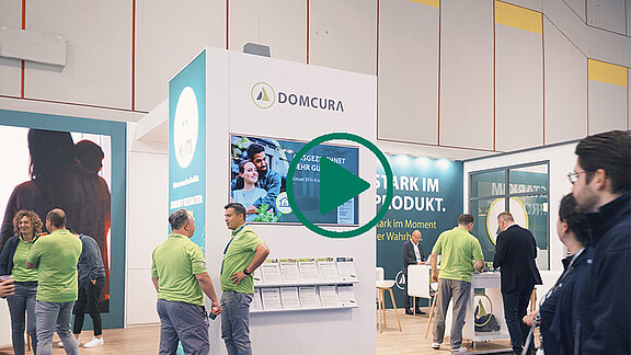 DOMCURA-Messestand auf der DKM in Düsseldorf mit mehreren Besuchern