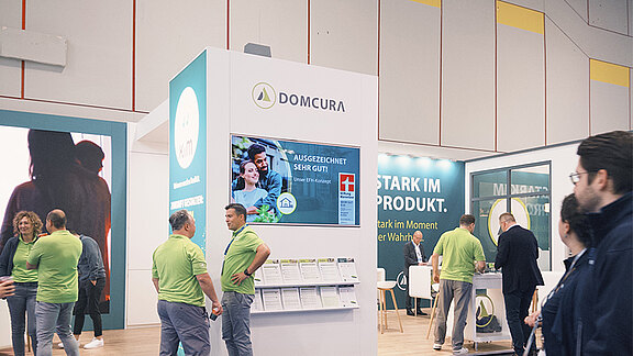 DOMCURA-Messestand auf der DKM in Düsseldorf mit mehreren Besuchern
